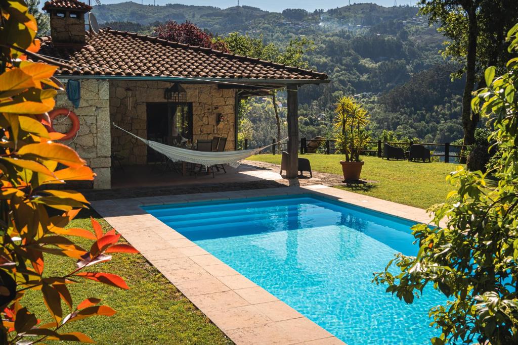 una piscina con una hamaca junto a una casa en Casa da Terra - Gerês, en Gerês