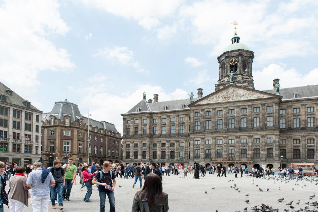 Un groupe de personnes marchant devant un grand bâtiment dans l'établissement The Amsterdam Hotel Apartment in the Center, à Amsterdam