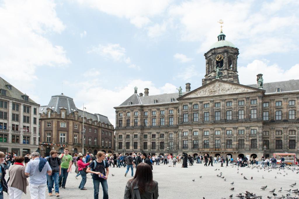 アムステルダムにあるThe Hotel Apartments in the Center of Amsterdamの大きな建物の前を歩く人々