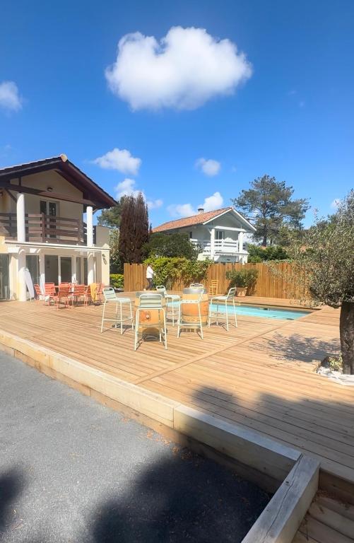 une terrasse avec une table et des chaises à côté d'une maison dans l'établissement Magnifique villa face au golf avec piscine au sel, à Lacanau