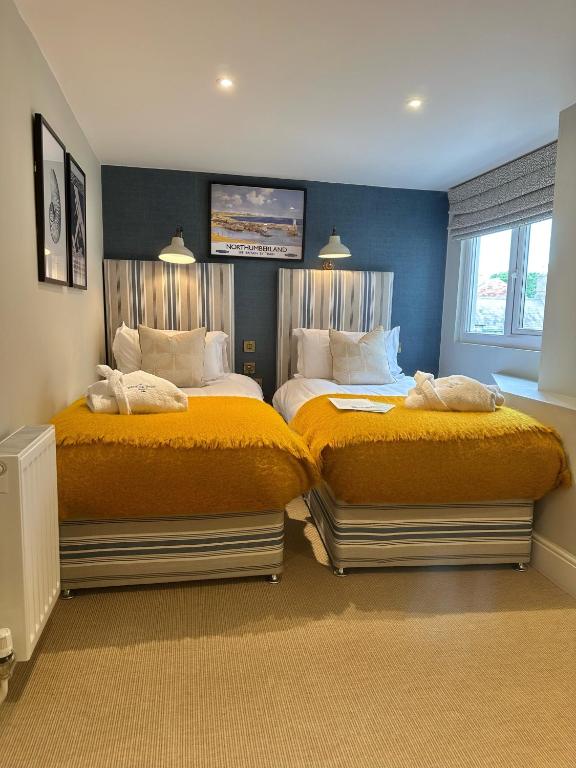 two beds in a bedroom with yellow sheets at The Whittling House in Alnmouth