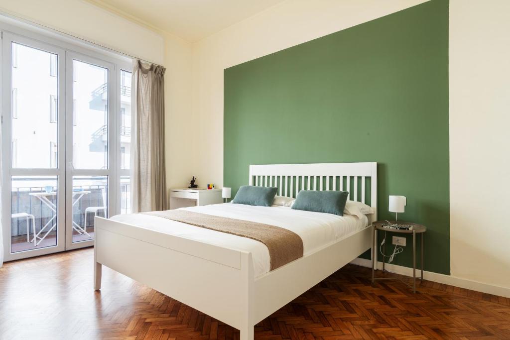 una camera con un letto bianco e una parete verde di Flora Flexyrent apartment AC a Milano