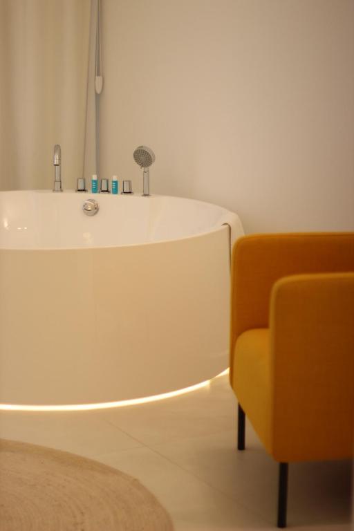 a bathroom with a tub and a yellow chair at Il Borghetto Resort & Spa in Tropea