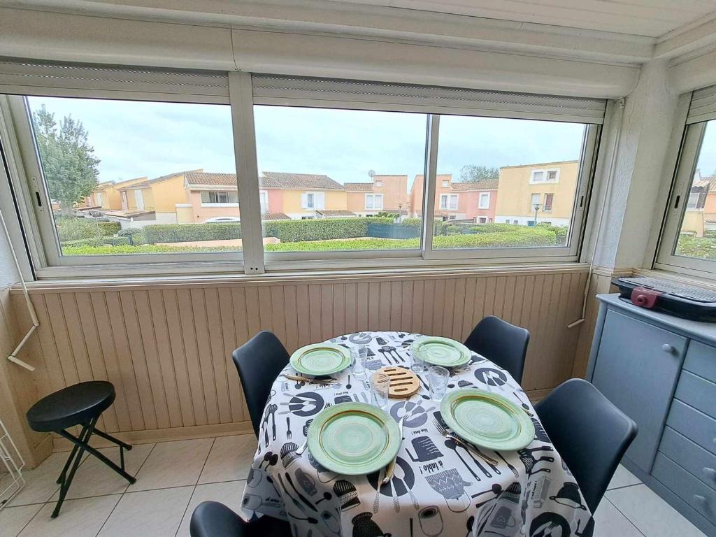 - une table avec des chaises et des assiettes dans la cuisine dans l'établissement Appartement 2 Pièces avec Piscine, Parking Privé et Proche Plage pour 4 Personnes - FR-1-326-820, à Marseillan