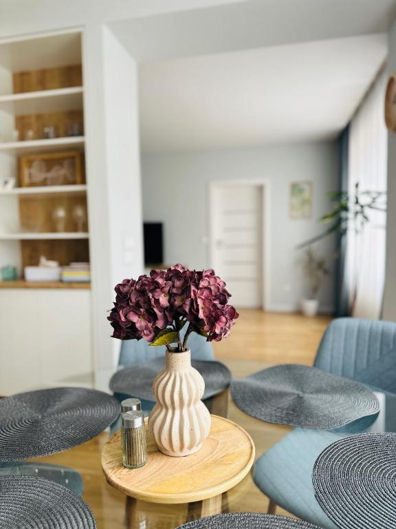 a vase with purple flowers on a table with chairs at Apartment Rebeka in Ružomberok