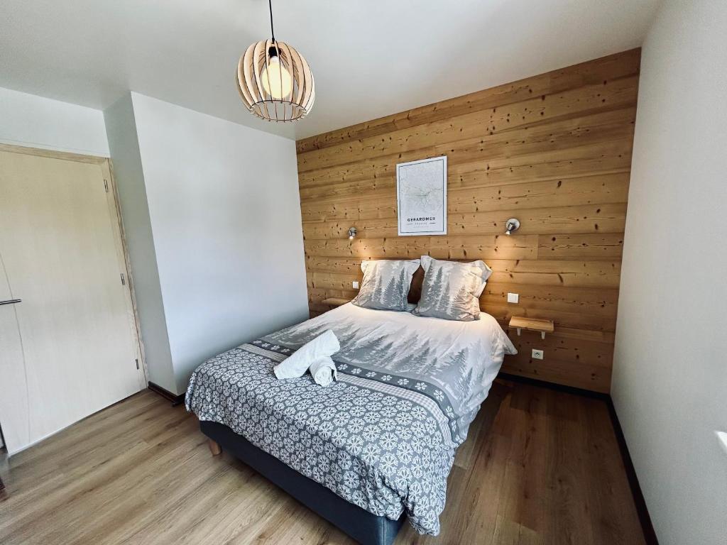 - une chambre avec un lit et un mur en bois dans l'établissement La Perle de l'Eau - au bord du lac, à Gérardmer