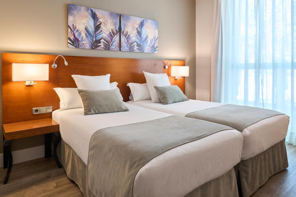 a hotel room with two beds and a desk at Hotel Puerta de Toledo in Madrid