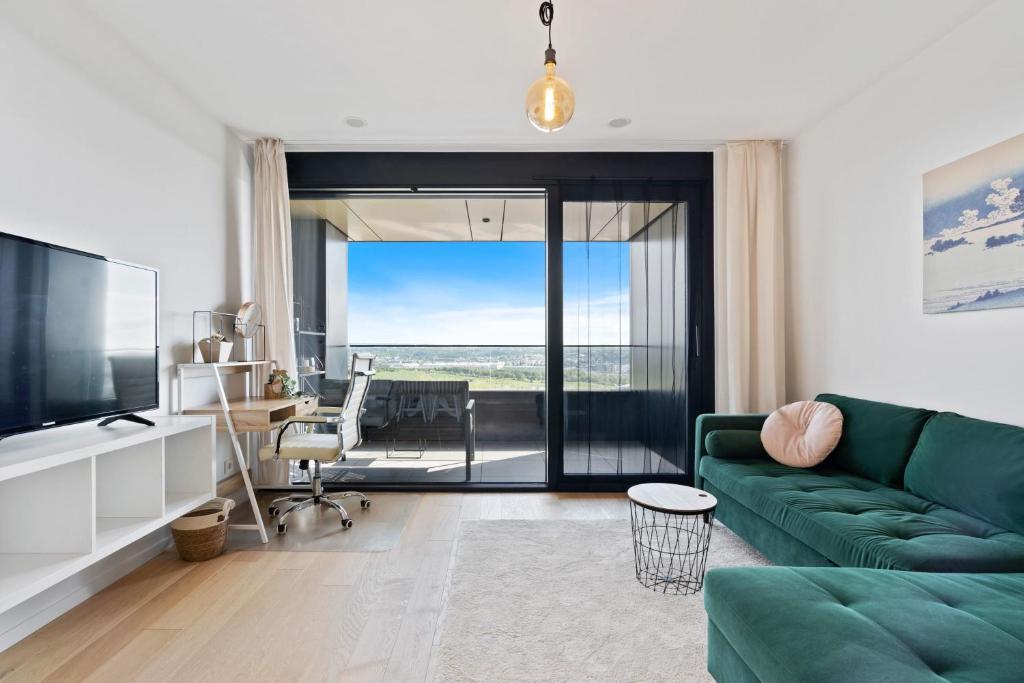 a living room with a green couch and a television at Luxurious City Retreat Balcony & Pool Access in Luxembourg