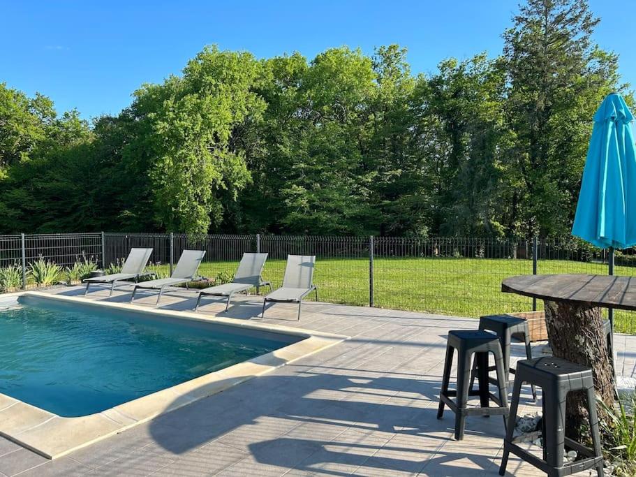 - une piscine avec des chaises, une table et un parasol dans l'établissement Maison avec piscine classée 3 étoiles, à Sainte-Trie
