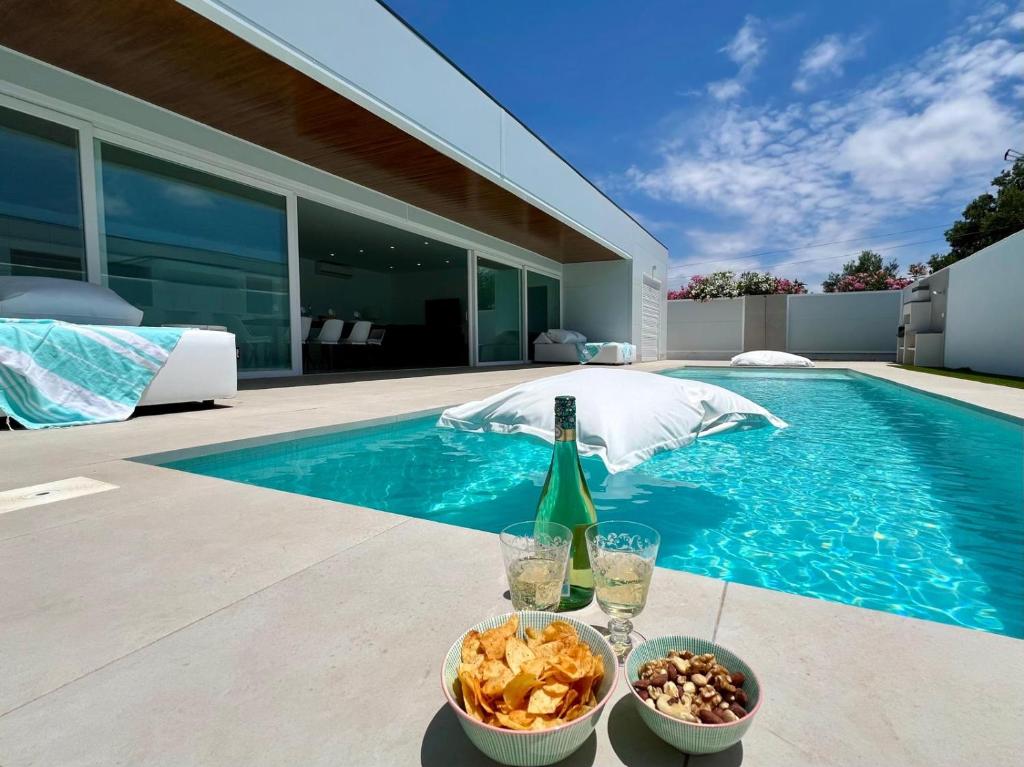 a bottle of wine and a bowl of food next to a swimming pool at Chalét El Nirvana in Chiclana de la Frontera