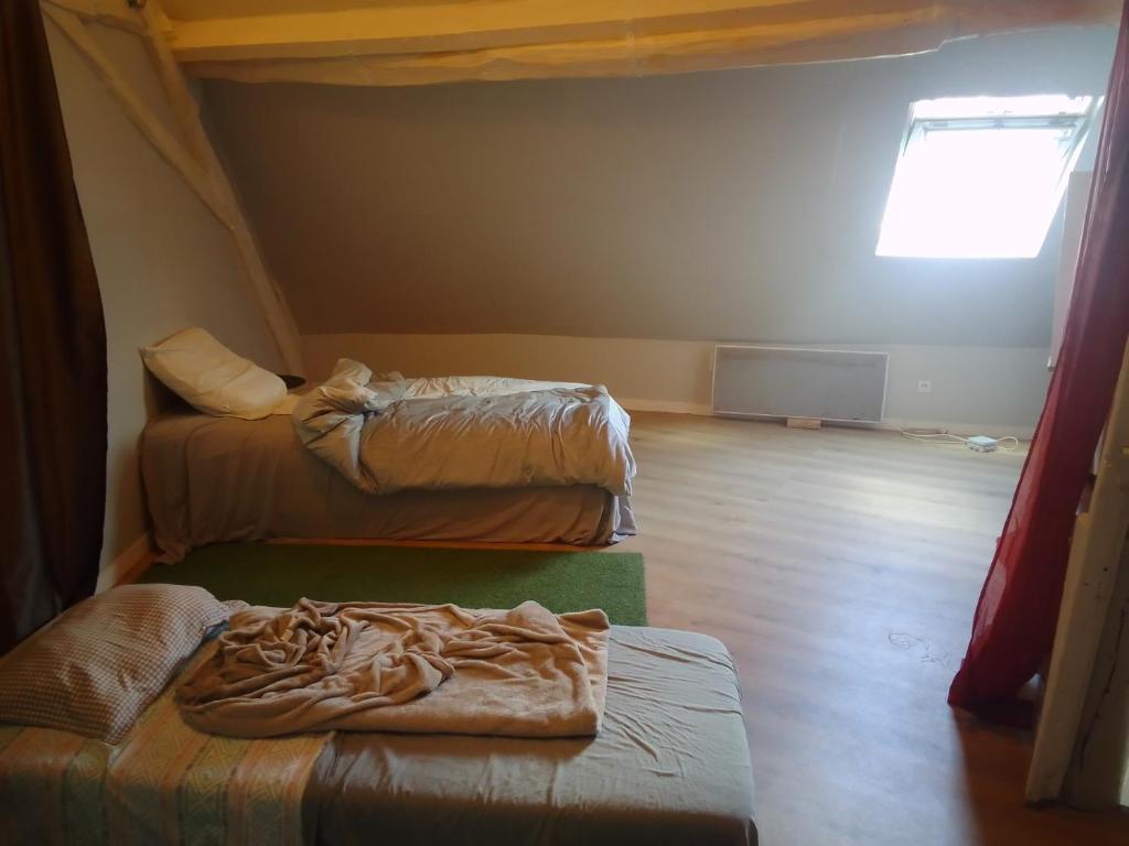 une chambre avec deux lits et une fenêtre dans l'établissement Chez Fernand, à Saint-Pierre-le-Moûtier