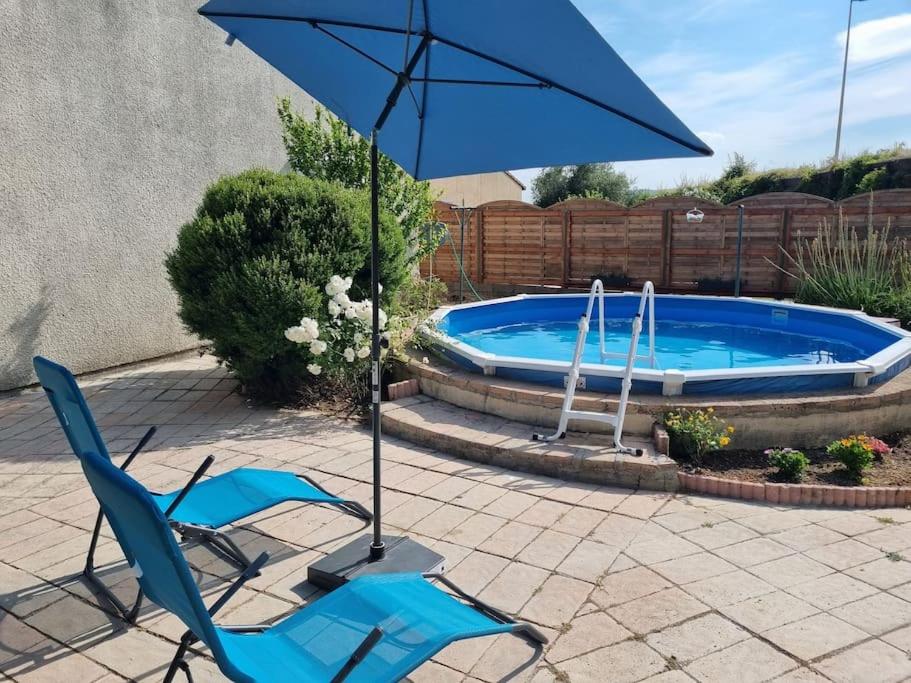 ein blauer Stuhl und ein Regenschirm neben einem Pool in der Unterkunft Vacances entre mer et montagne in Alès