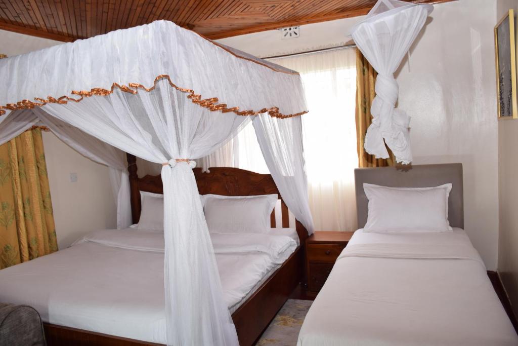 - une chambre avec 2 lits dotés de rideaux blancs dans l'établissement Zarita Boutique Hotel, à Nairobi