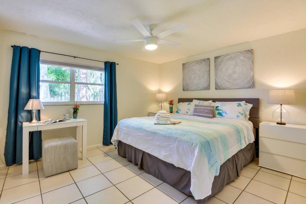 a bedroom with a bed with blue curtains and a window at Coconut Cove Mid-long term stays available Walk to Downtown Trolly to BEACHES in Sarasota