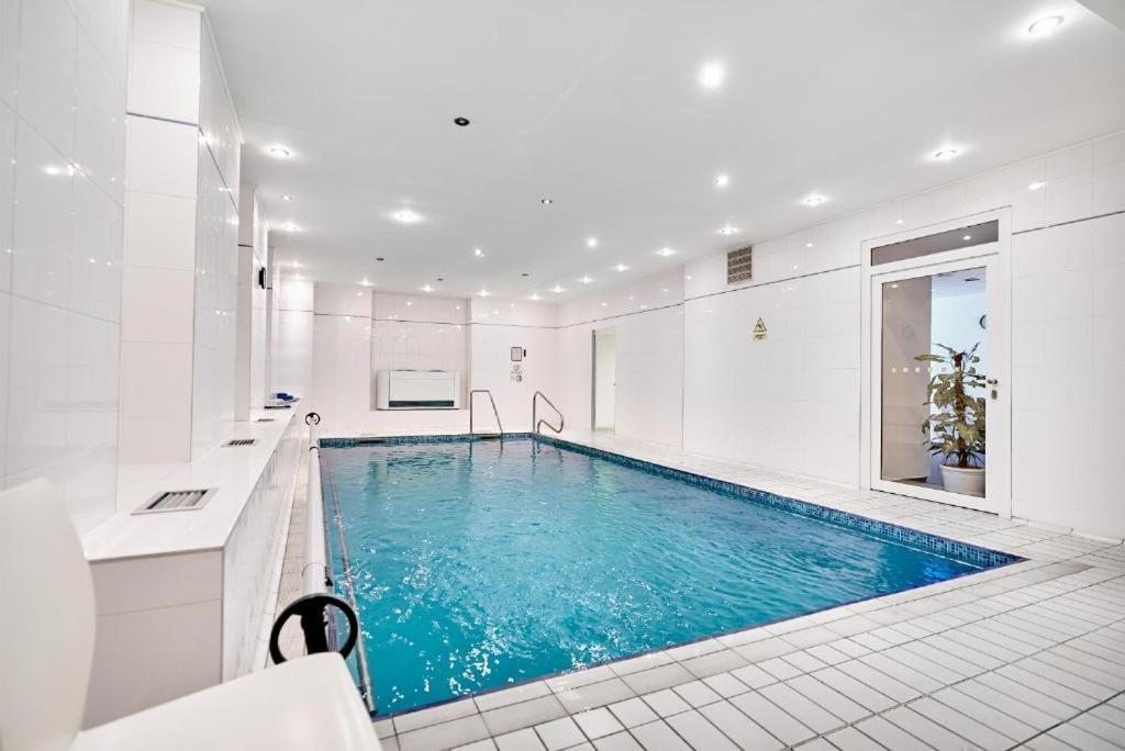 - une grande piscine dans une salle de bains blanche avec une piscine bleue dans l'établissement Hotel Flora, à Mariánské Lázně