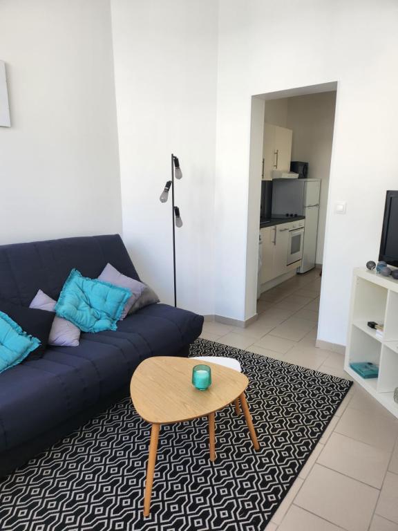 un salon avec un canapé bleu et une table dans l'établissement La Coquille, au Crotoy