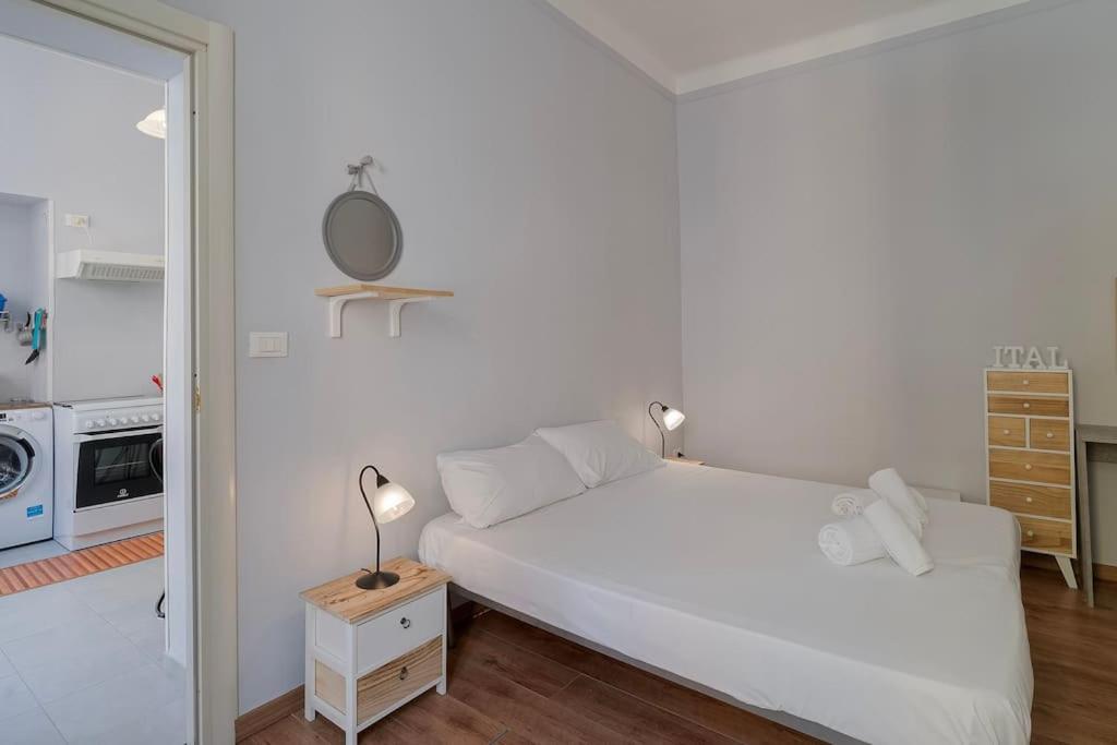 una camera da letto bianca con un letto e uno specchio di Bilocale Mazzini a Ventimiglia