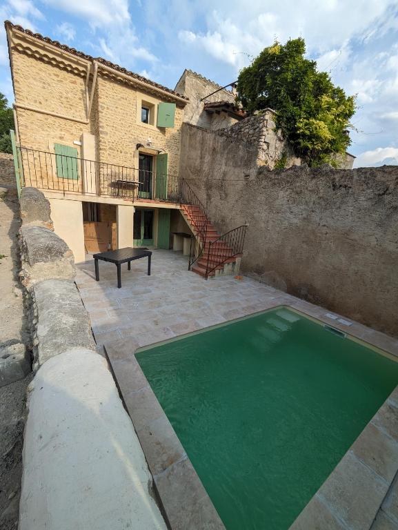une piscine d'eau verte en face d'un bâtiment dans l'établissement Maison de village en Provence, à Saint-Roman-de-Malegarde