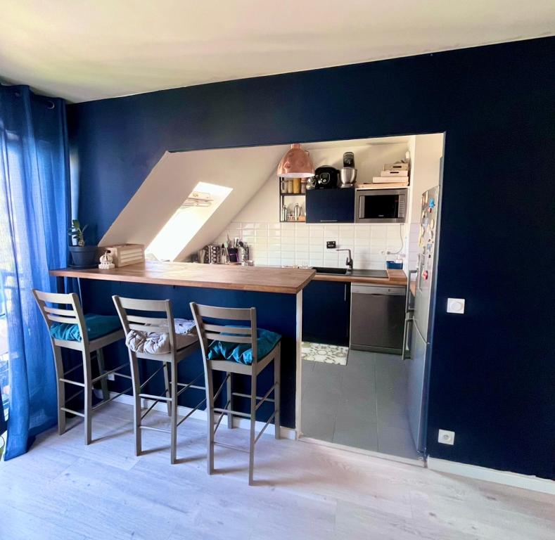 a kitchen with blue walls and a counter and chairs at Apt central entre stade de France et villette in Aubervilliers