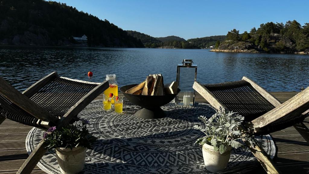 a table with two chairs on a dock next to a lake at Moderne hytte i vannkanten med tilgang til brygge og båt in Risør