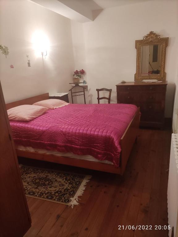 une chambre avec un lit, une commode et un miroir dans l'établissement Maison de village, à Les Cammazes