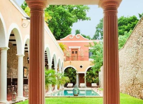 une grande maison avec une piscine et des colonnes dans l'établissement Hotel Hacienda Mérida VIP, à Mérida