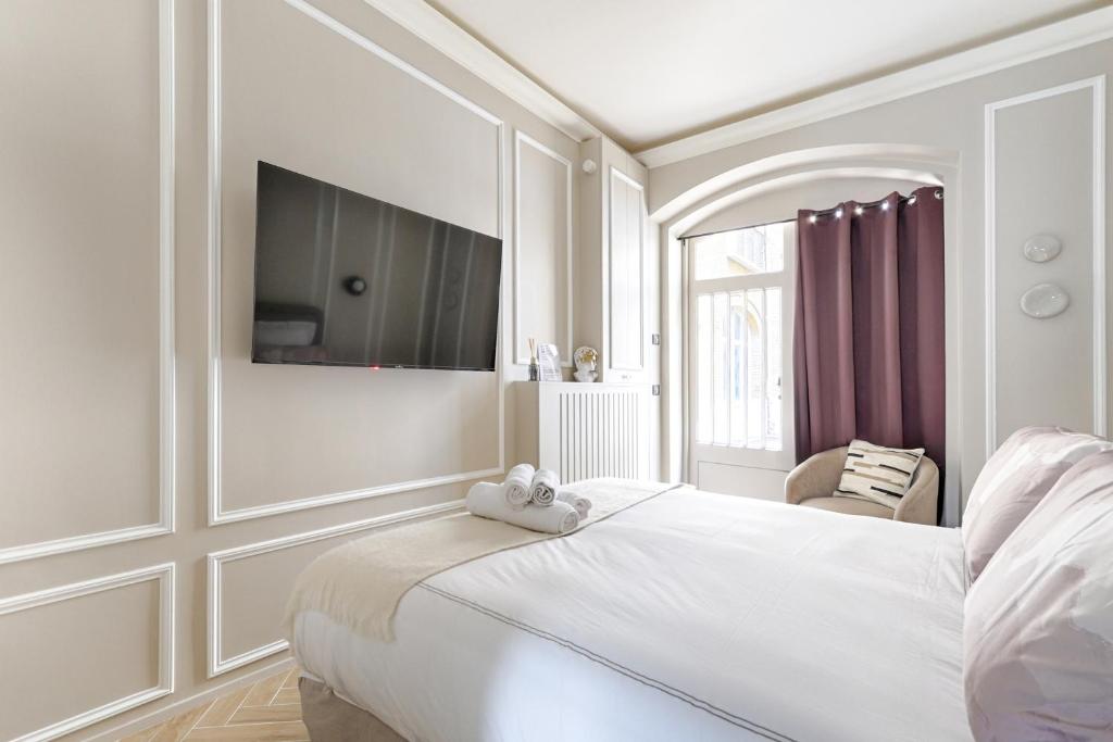 une chambre blanche avec un lit et une télévision au mur dans l'établissement Luxury and Design Studio Invalides, à Paris