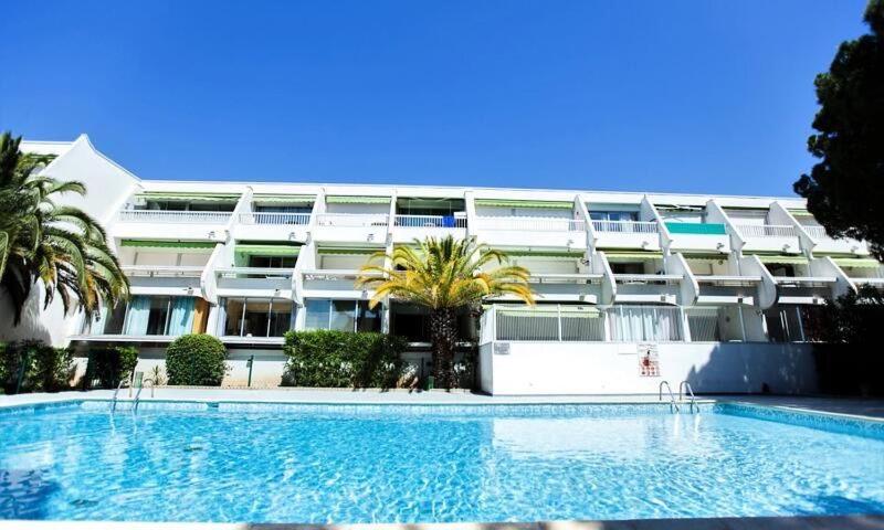 un grand bâtiment avec une piscine en face d'un bâtiment dans l'établissement Studio très beau quartier le Ponant avec piscine Résidence Port Vincent, à La Grande Motte