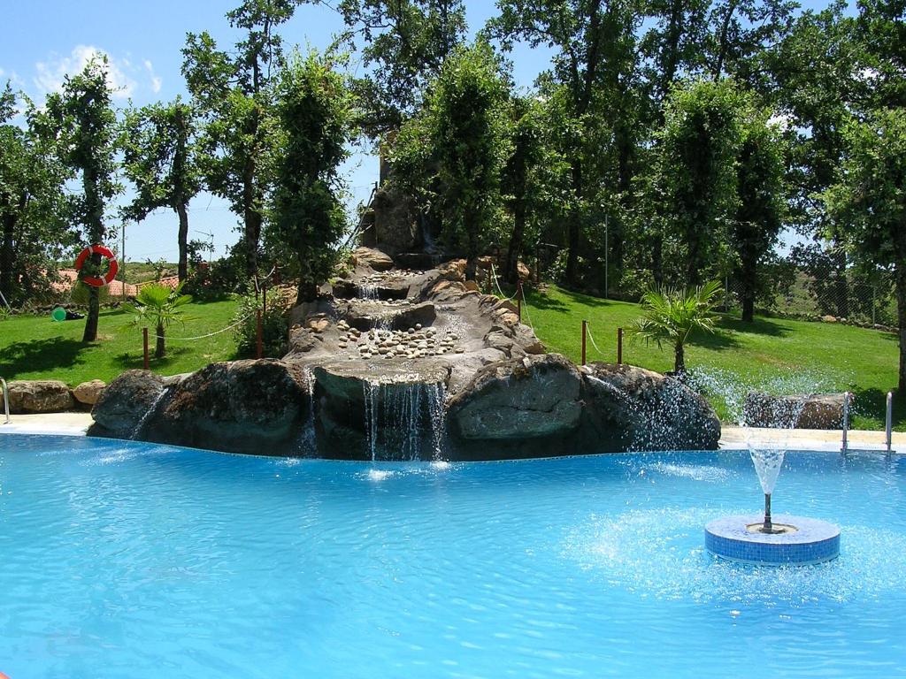 a fountain in a swimming pool in a park at CAMPING-BUNGALOWS-CABAÑAS LA VERA in Jarandilla de la Vera