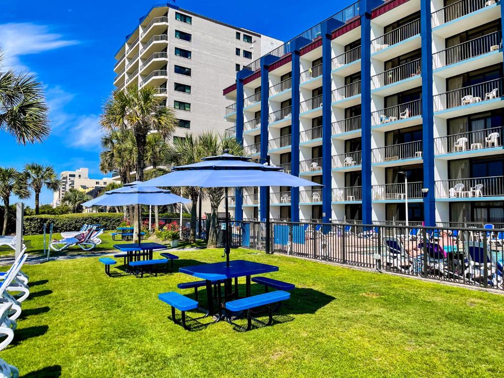 a group of tables and umbrellas in front of a hotel at Grande Shores in Myrtle Beach