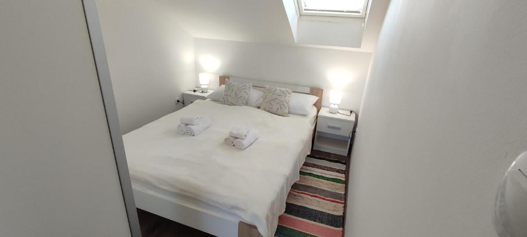 a small bedroom with a bed with white sheets and pillows at Apartman BS in Velika Gorica