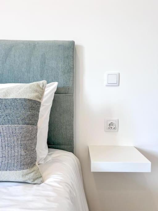 a bed with a green headboard and a white pillow at The Cate House - Casa renovada a 3 minutos do Centro Histórico in Lagos