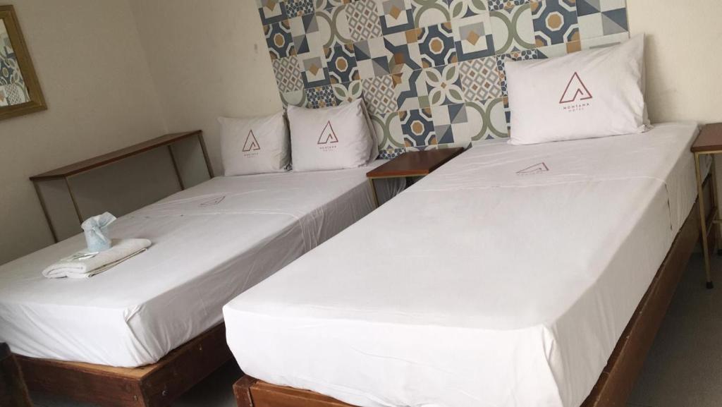 two beds in a room with white sheets and pillows at Hotel Montana in Villahermosa