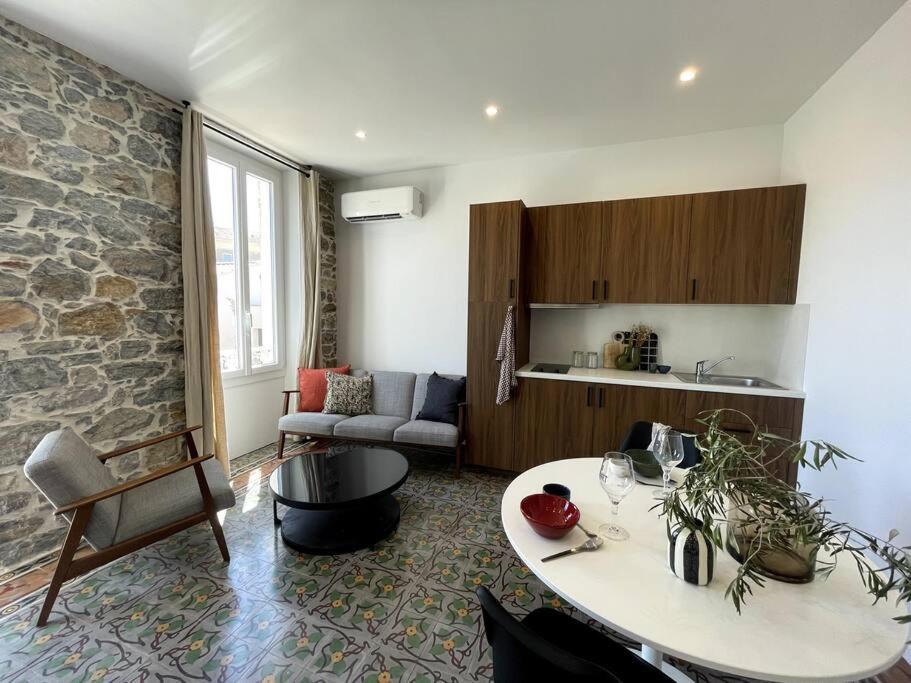 a living room with a table and a stone wall at Appartement spacieux, confort et climatisé à 500m de la plage in Carqueiranne