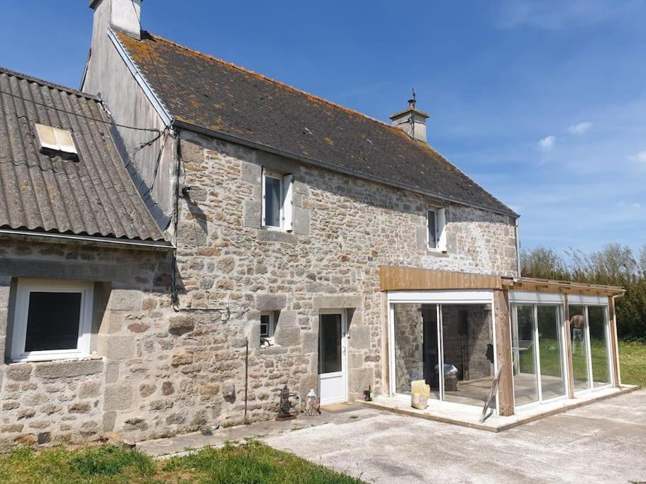 - un vieux bâtiment en pierre avec une grande porte en verre dans l'établissement Confortable et Fonctionnelle, à Cléder