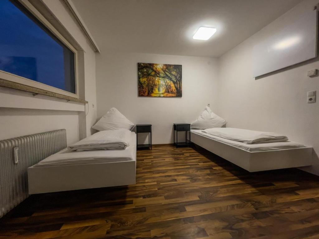 two beds in a room with wooden floors at Budget Studio - 2 Einzelbetten - Parkplatz in Dornbirn