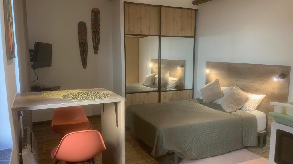une chambre avec un lit, un bureau et un miroir dans l'établissement Grands Buffets hébergement Studio Narbonne, à Narbonne