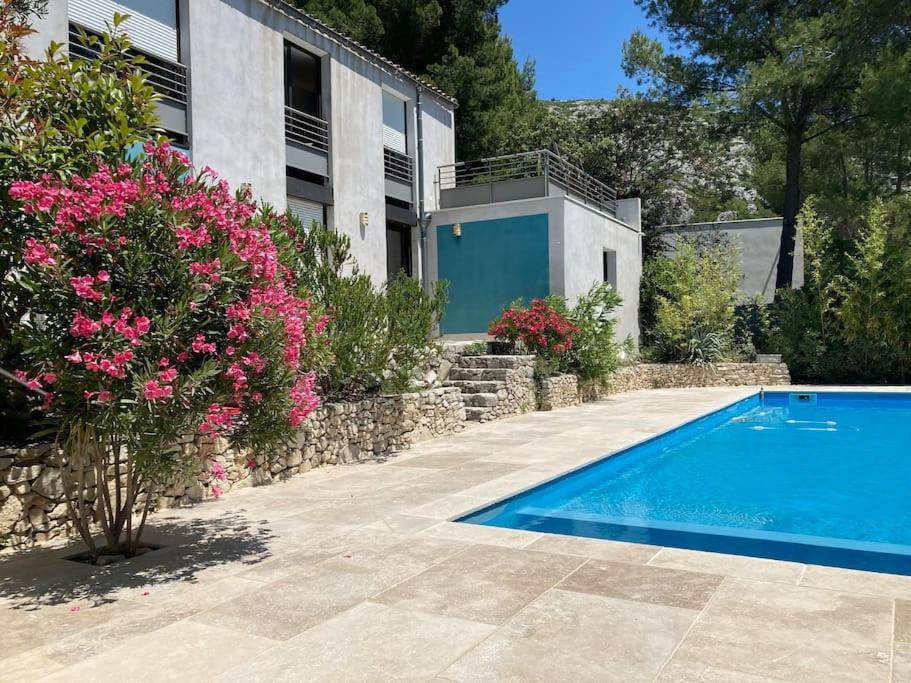 - une piscine en face d'une maison ornée de fleurs roses dans l'établissement Magnifique villa avec piscine en Provence, à Gémenos