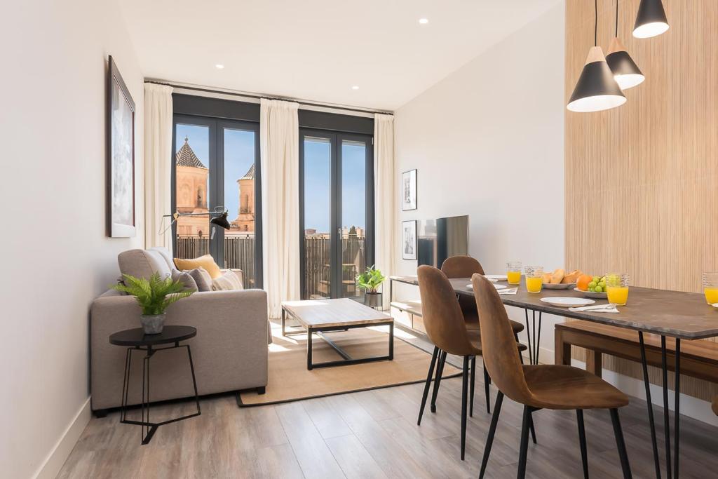 a kitchen and living room with a table and chairs at Livemálaga Alta Suite & Parking in Málaga