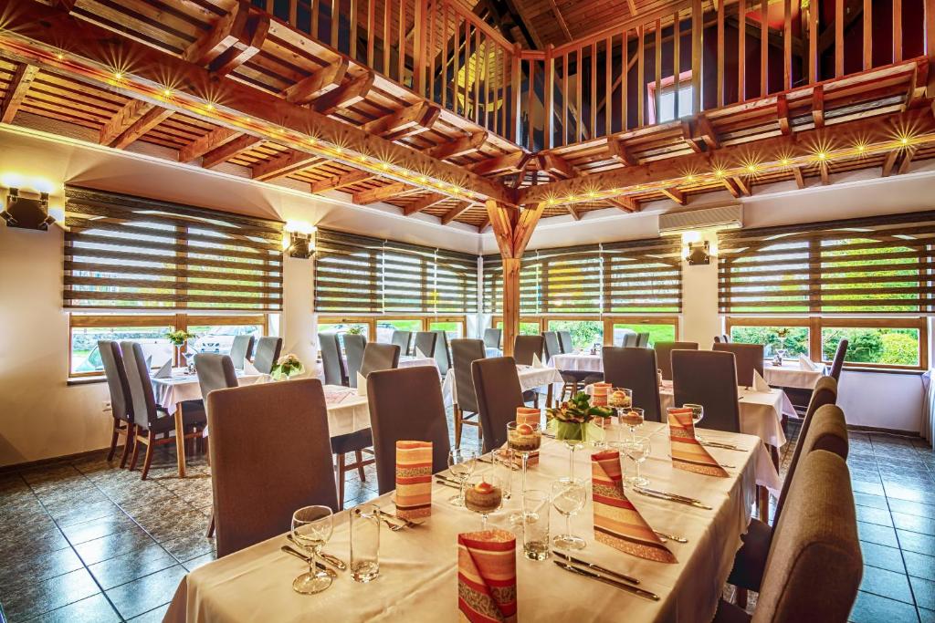een restaurant met lange tafels, stoelen en ramen bij Penzion Almada in Zvolen
