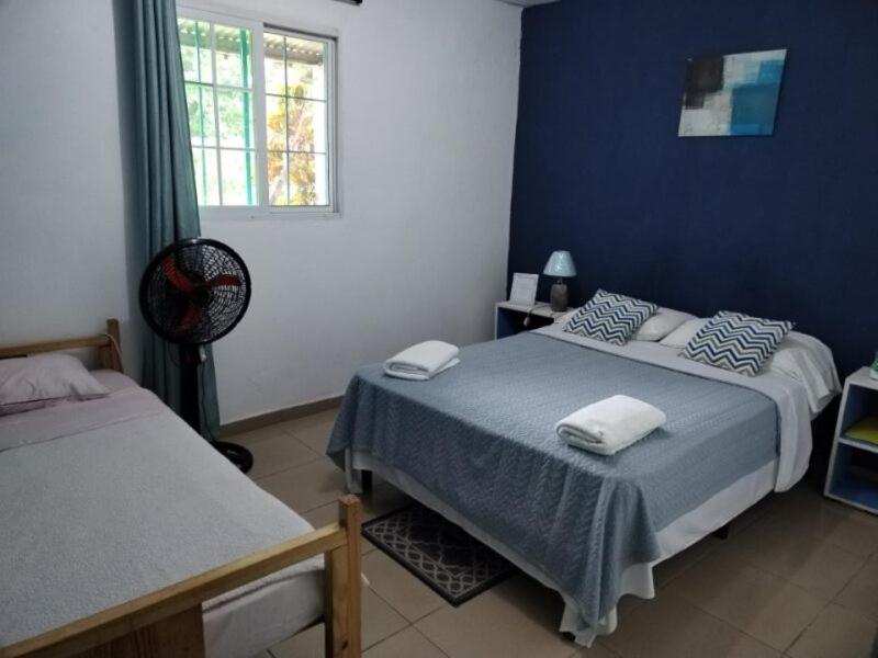 1 dormitorio con 2 camas y pared azul en Casa Hostal Bouvá, en El Valle