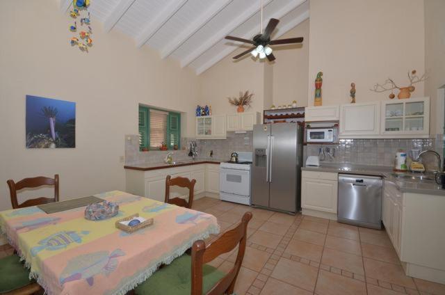 a kitchen with a table and a kitchen with a ceiling fan at Kas Berde Kanti Laman in Kralendijk