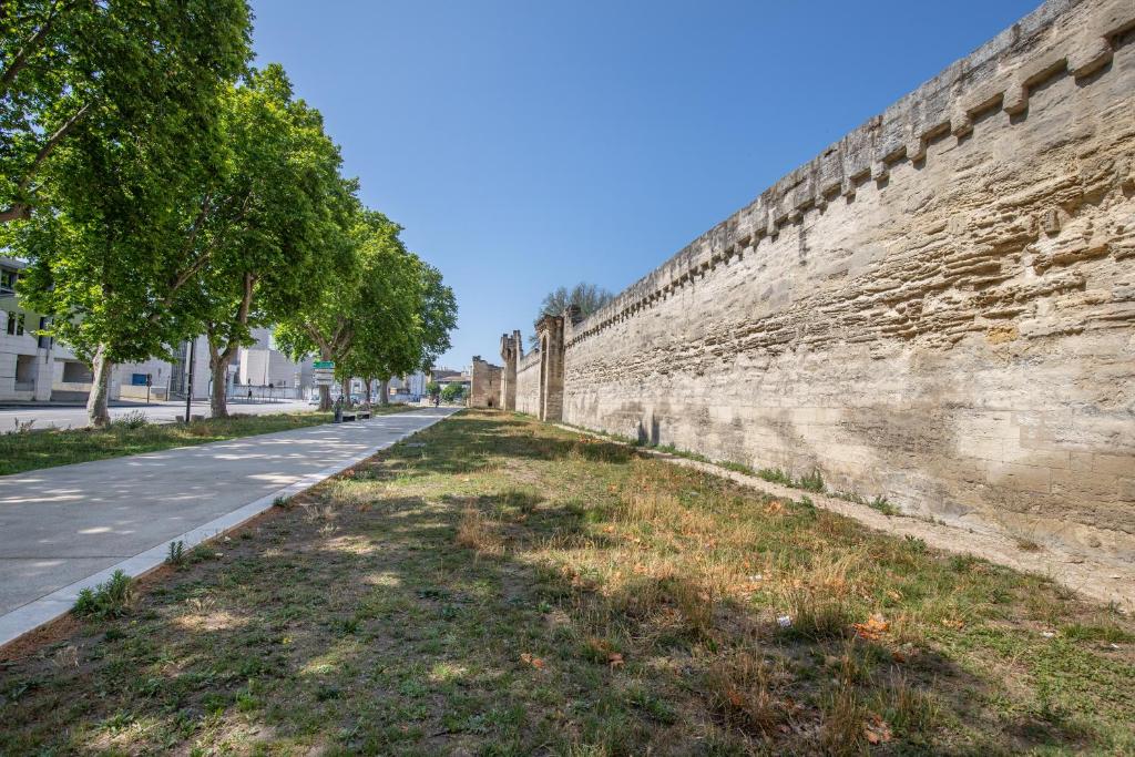 un grand mur avec des arbres sur le côté d'une rue dans l'établissement Studio aux portes des remparts !, à Avignon