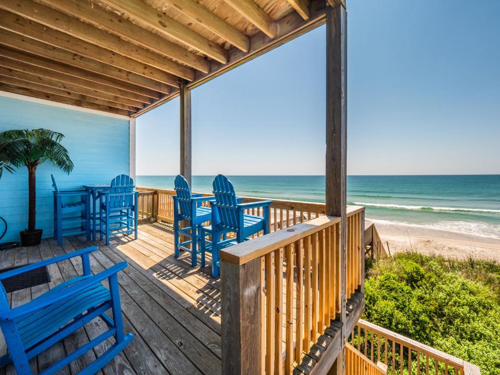 a deck with blue chairs and the beach at Sand By Me in Surf City