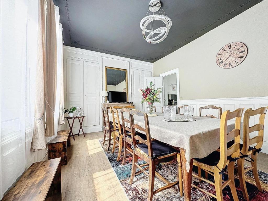 a dining room with a table and chairs and a clock at A1 Champagne Résidence - 200 m2 14 personnes 2 toilets 4 showers - hyper centre - Chalons en Champagne in Châlons-en-Champagne