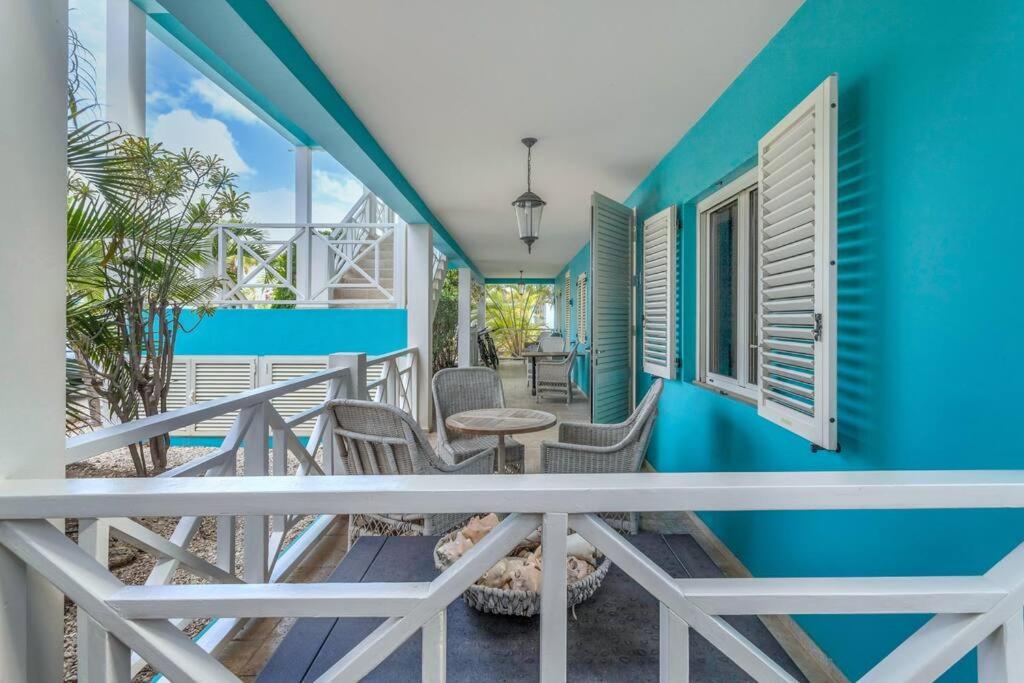 a balcony with chairs and a table and a blue wall at Ocean Breeze Apartments #33 in Kralendijk