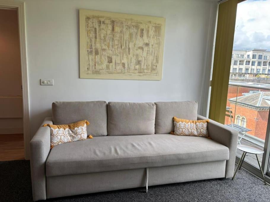 a gray couch in a living room with a window at Luna Stays Ltd apartment 37 in Birmingham