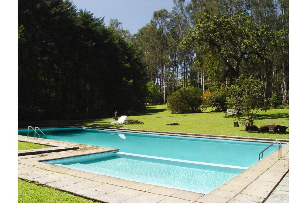 una gran piscina azul en un patio con árboles en Hotel Refazenda, en Visconde De Maua