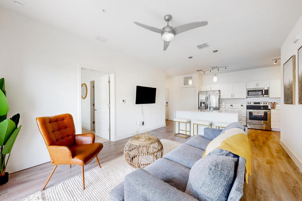 a living room with a blue couch and a kitchen at 2 Mi to UF Campus! Dog-Friendly Condo w/ Pool in West Hills
