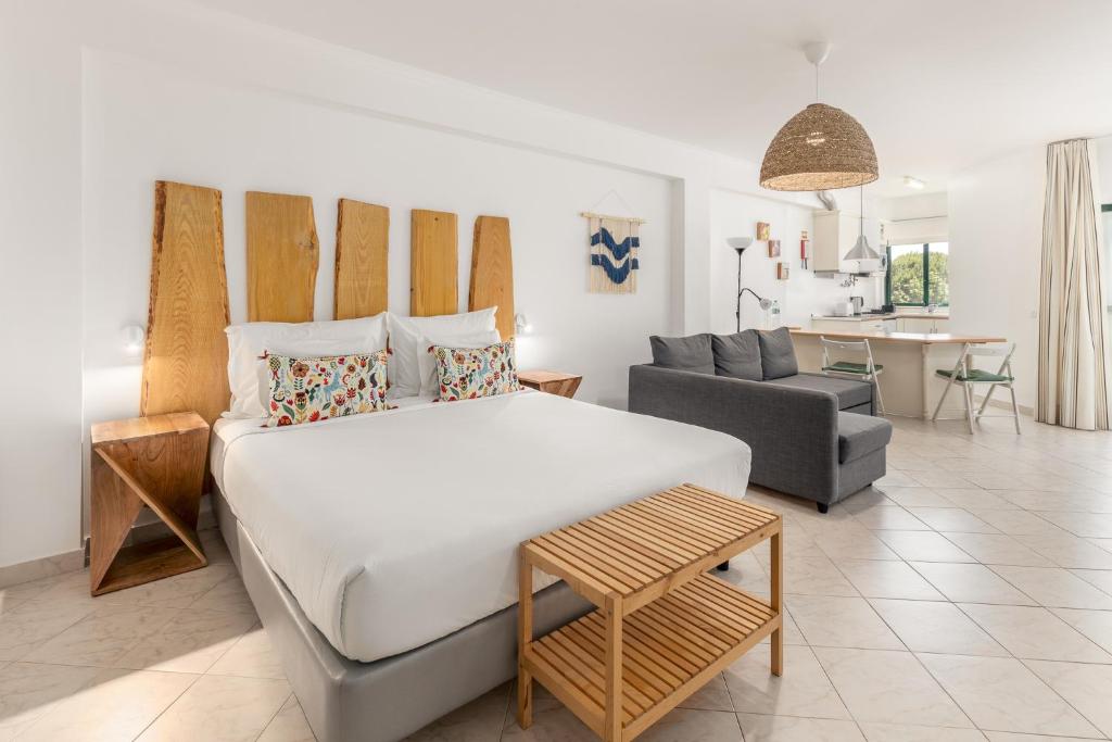 a bedroom with a large white bed and a couch at Estudios Salinas - Fuseta in Fuzeta
